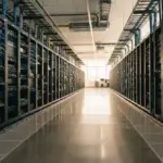 Modern server racks stretch down a sunlit aisle in a pristine data center